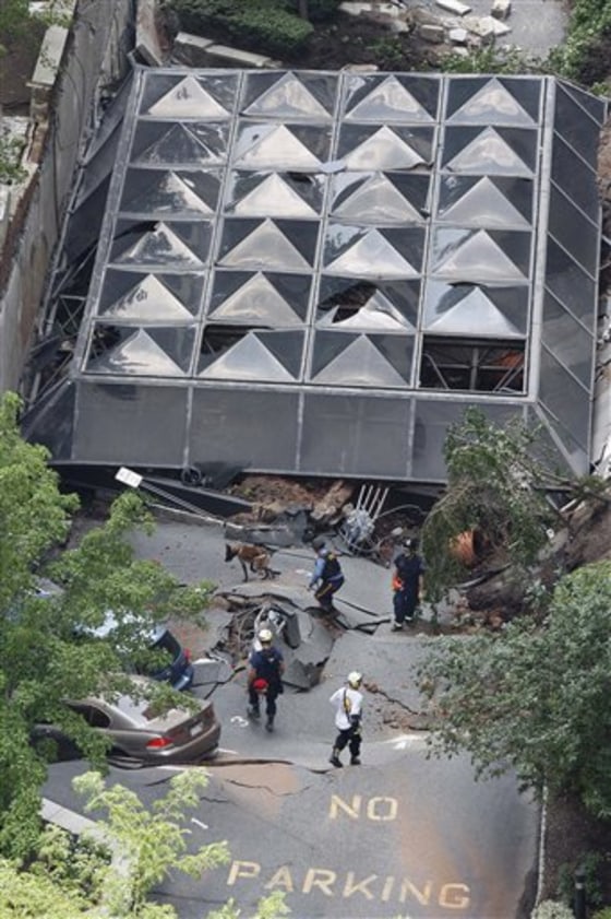 A police officer walks with a search dog as other rescue officials walk on the rubble after the front of an apartment building and a parking garage collapsed Friday in Hackensack, N.J.